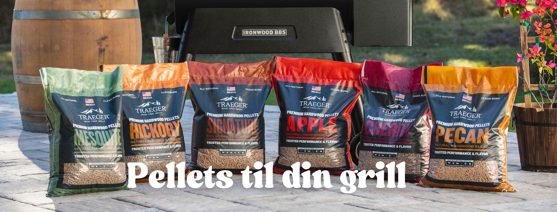 Traeger Pellets i poser, stilt opp foran en traeger Ironwood 885 pelletsgrill på en platting i en hage